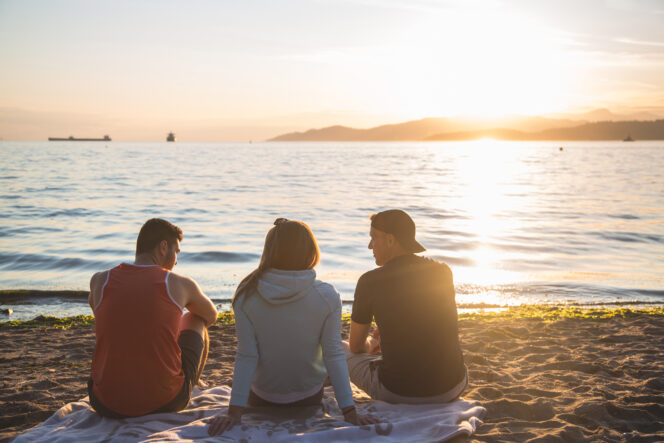 Three friends enjoying a sunset at the beach in Vancouver