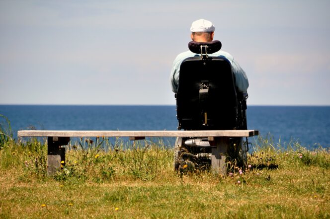 A man in a wheelchair looks at the ocean