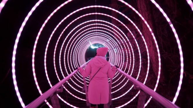 A woman walks through a tunnel of light at Capilano Suspension Bridge