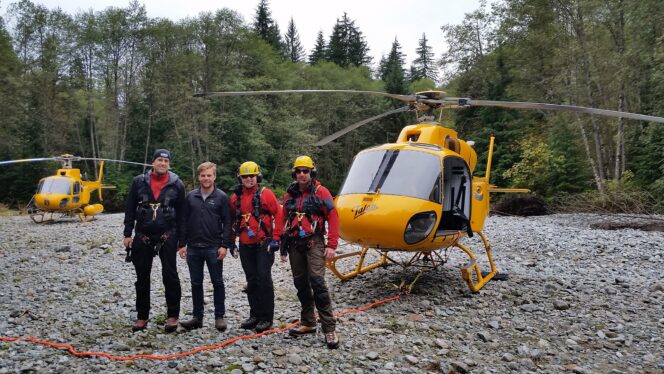 Members of Coquitlam Search and Rescue pose in front of a helicopter
