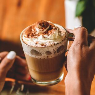 Close up of a woman's hands holding a mug of hot chocolate with whipping cream
