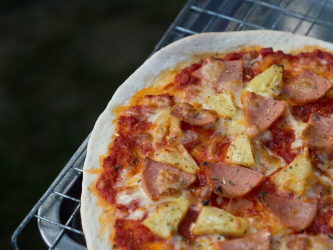 A close up of a Hawaiian pizza with ham and pineapple