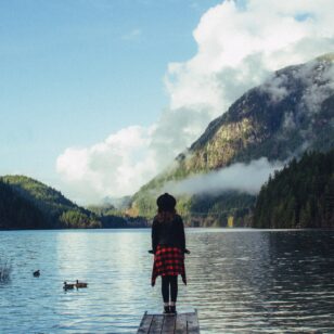 A woman stands on the shore of Buntzen Lake near Vancouver
