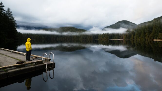 A man in a yellow coat stands on a floating dock at Sasamat Lake near Vancouver