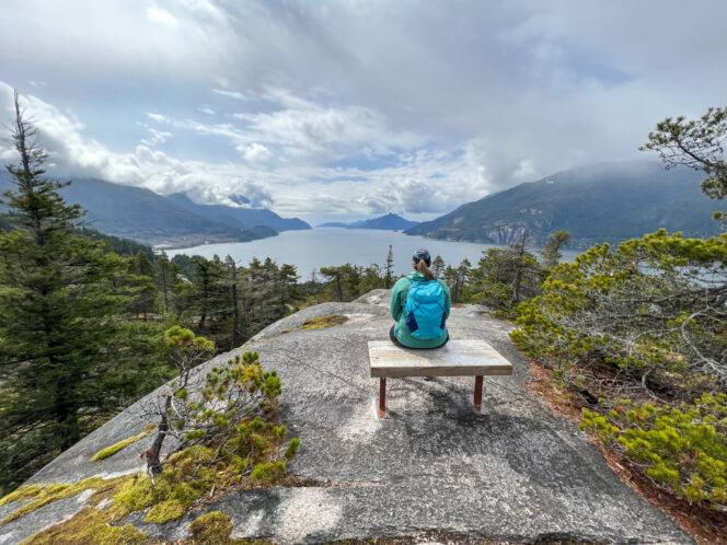 A woman sits on a bench at Quercus Viewpoint at Murrin Provincial Park
