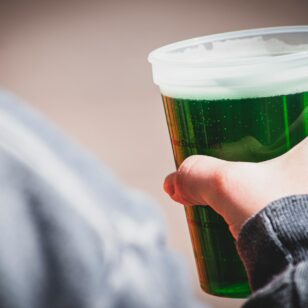 A drinker holds a glass of green beer for St. Patrick's Day