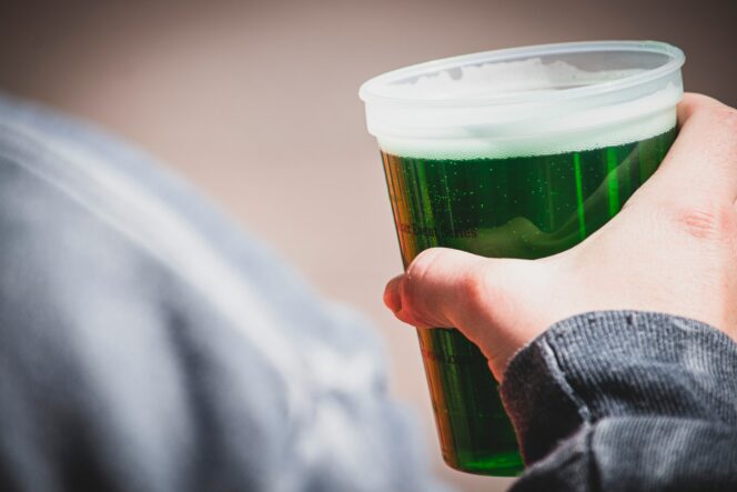 A drinker holds a glass of green beer for St. Patrick's Day