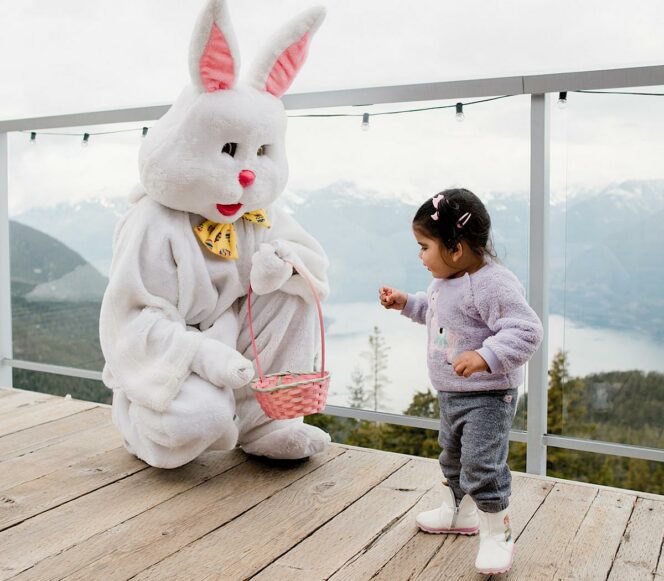 A person in an Easter bunny costume gives candy to a child at the Sea to Sky Gondola