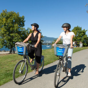 Two people ride Mobi bike share bikes in Vancouver.