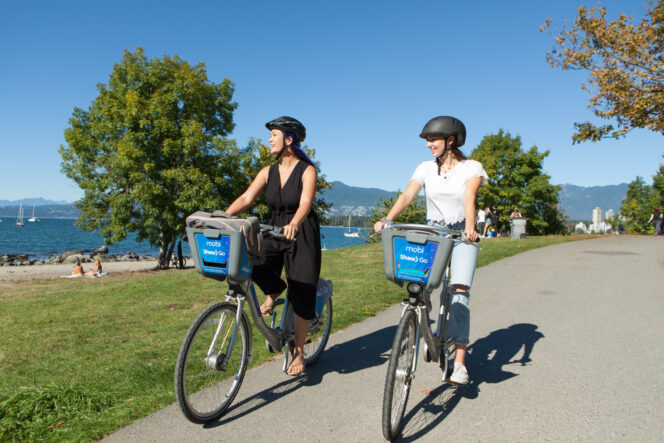 Two people ride Mobi bike share bikes in Vancouver.
