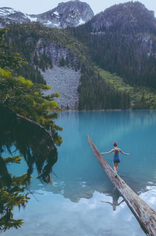 A hiker balances on a floating log at Joffre Lakes Provincial Park