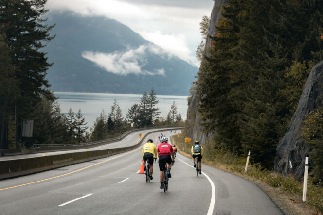 Cyclists biking the Sea-to-Sky Hwy during the RBC GranFondo Whistler. 