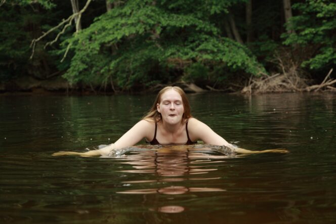 A woman cold plunges in a creek