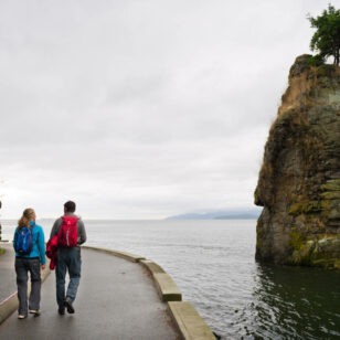 A couple walks along the Stanley Park Seawall in Vancouver on a rainy day.
