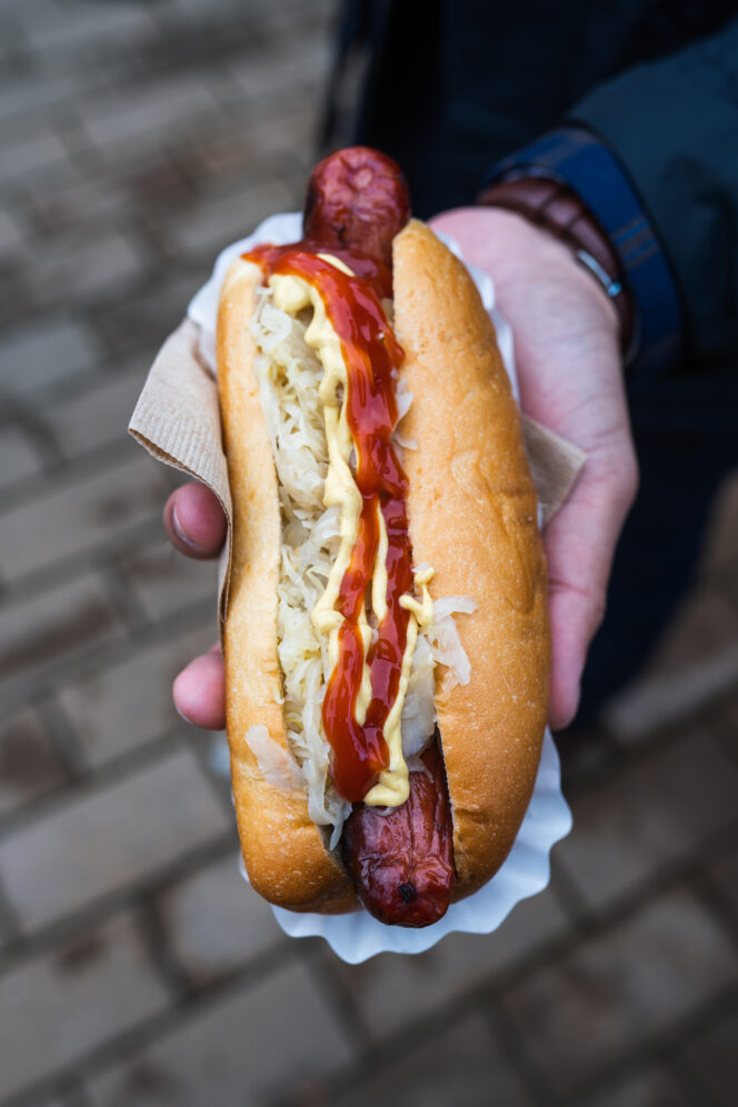 Close up of a hand holding a bratwurst at the Vancouver Christmas Market