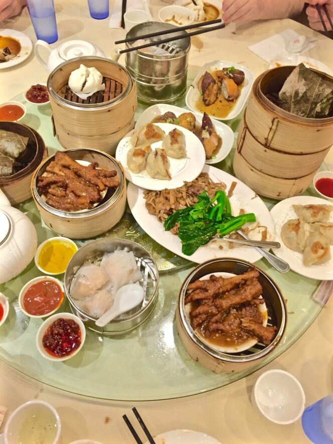 A table covered in dim sum dishes in bamboo steamer baskets and on plates. 