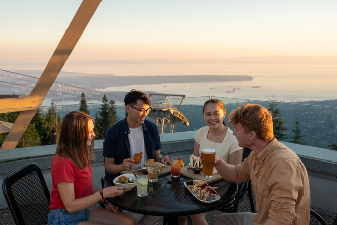 A group of four people enjoy food on the patio at Altitudes Bistro at Grouse Mountain