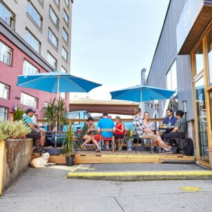 People sit under umbrellas on the patio at Odd Society Spirits in Vancouver