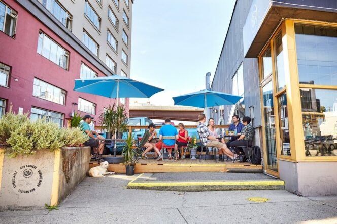People sit under umbrellas on the patio at Odd Society Spirits in Vancouver
