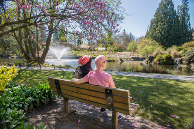 Two people sit on a bench in VanDusen Botanical Garden. 
